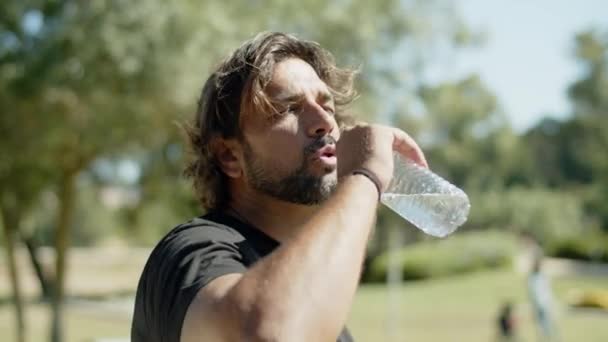 Close-up shot van vermoeide atleet drinkwater tijdens de training — Stockvideo