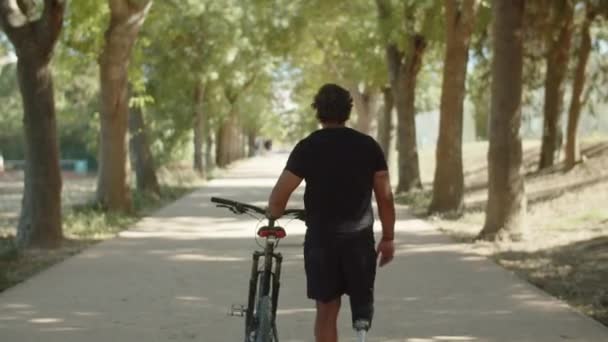 자전거를 타고 골목을 걸어가는 사람의 뒷모습 — 비디오