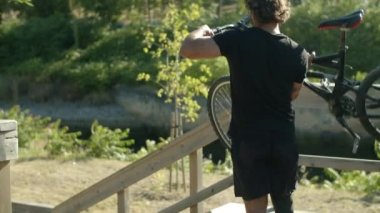 Motoru kaldırırken ve merdivenlerden inerken odaklanmış bir adam.