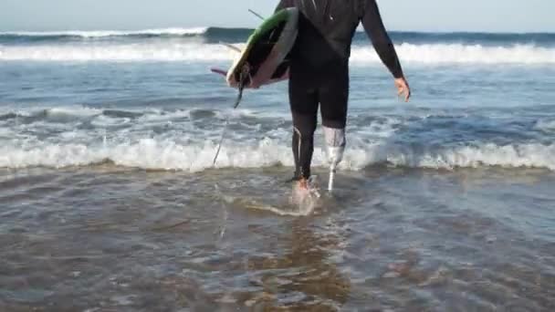 Deportista con discapacidad que va a las aguas oceánicas para surfear — Vídeos de Stock