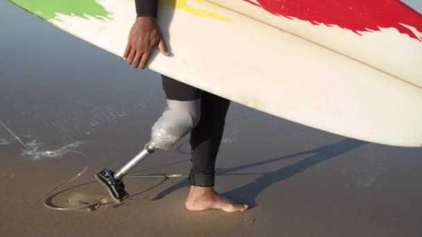 ビーチに沿って歩く障害のあるアスリートの垂直運動 — ストック動画