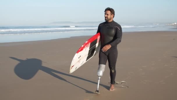 Långskott av allvarliga surfare med funktionshinder promenader längs stranden — Stockvideo