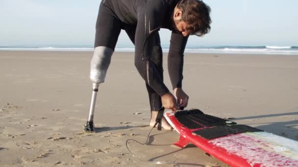 Вертикальний рух людини з інвалідністю прив'язування повідця на дошці для серфінгу — стокове відео