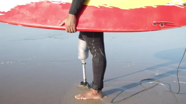 Primer plano de las piernas de surfista con discapacidad en la playa de arena — Vídeos de Stock