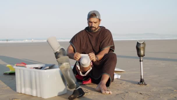 Vorderansicht eines nachdenklichen Surfers mit Beinprothese an der Küste — Stockvideo