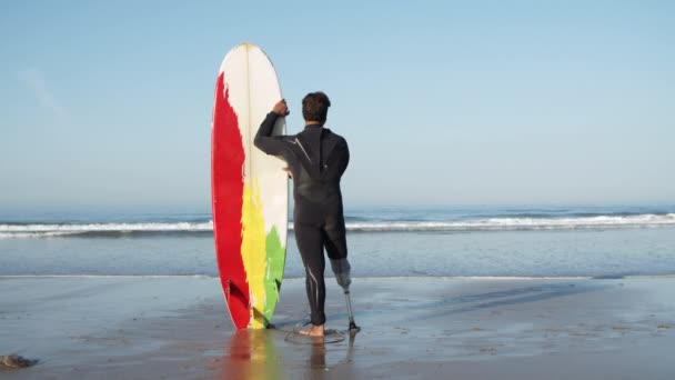 Vista posteriore del surfista con disabilità in piedi accanto all'oceano — Video Stock