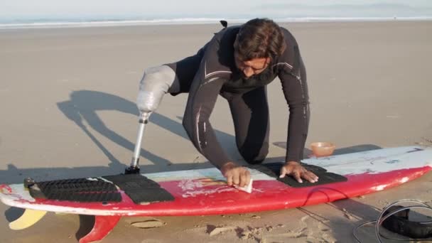 Tiro medio de hombre con discapacidad encerado superficie de la tabla de surf — Vídeos de Stock