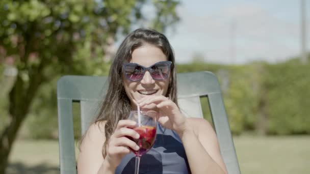 O femeie fericită în bikini întinsă pe șezlongul de soare, bea cocktail — Videoclip de stoc