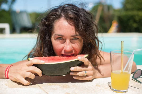 Atractiva mujer comiendo sandía en la piscina —  Fotos de Stock