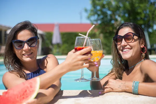 Mujeres bonitas bebiendo cóctel brillante en la piscina — Foto de Stock