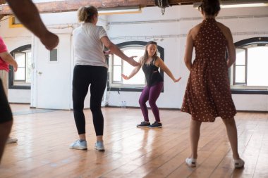 Mutlu genç eğitmen Twist dansı adımlarını öğretiyor.