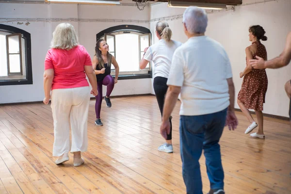 Komik, genç, beyaz bir öğretmen dans adımları gösteriyor.