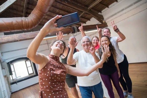 Cheerful senior dance group taking picture after class in studio