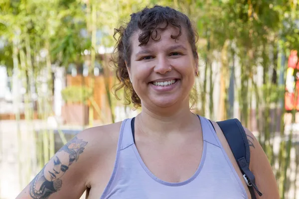 Kıvırcık saçlı, spor yapan gülen kadının portresi.