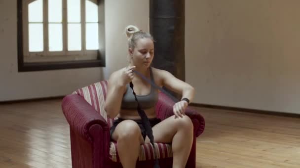 女性ボクサー座っていますアームチェアとローリング包帯で手 — ストック動画