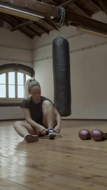 Vertikální záběr zaostřené samice kickboxer šněrování boty v tělocvičně — Stock video