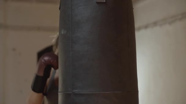 Mittlerer Schuss einer ernsthaften Kickboxerin gegen Boxsack — Stockvideo