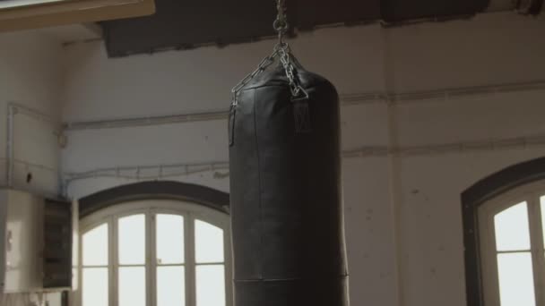 Medium shot of leather heavy bag hanging from ceiling in gym — Stock Video