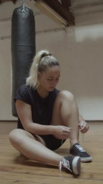 Kickboks antrenmanından önce ayakkabılarını bağlayan hoş bir kadının ön görüntüsü.