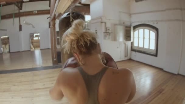 Zadní pohled na sebevědomé ženy punching těžký pytel — Stock video