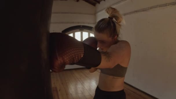 Tiro de seguimiento de la mujer en guantes de boxeo saco de boxeo pesado — Vídeos de Stock