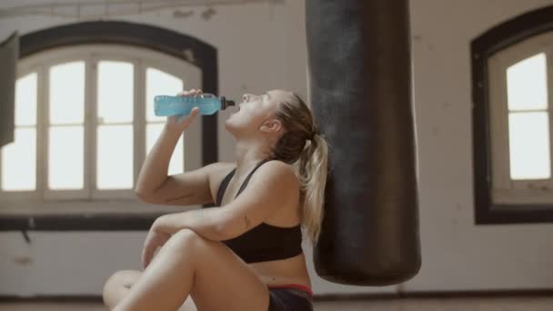 Widok boczny atletycznej kobiety pijącej izotoniczne w siłowni — Wideo stockowe