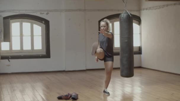 Långskott av allvarliga kvinnliga idrottsman svängande ben i gymmet — Stockvideo