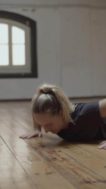 Средний снимок концентрированной молодой женщины, делающей отжимания в спортзале — стоковое видео