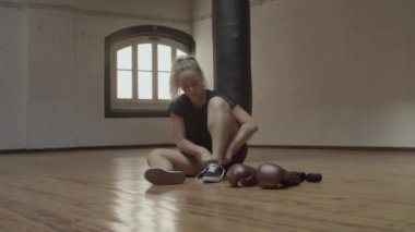 Genç bir kadının kickboks salonunda spor ayakkabılarını bağlama ihtimali çok düşük.
