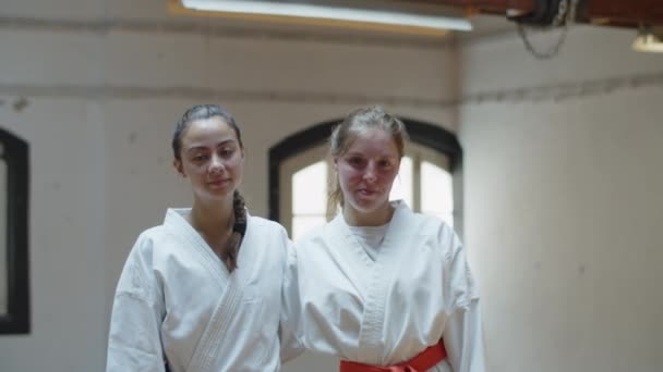 Widok z przodu szczęśliwych dziewcząt w kimonach stojących na siłowni i przytulających — Wideo stockowe