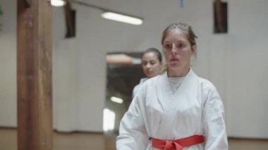Odaklanmış kızların spor salonunda karate hareketleri ön planda.