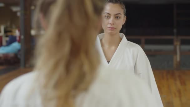 Tiro medio de mujeres combatientes inclinándose antes del entrenamiento de karate — Vídeos de Stock