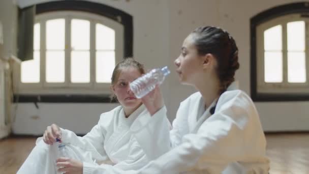 Side view of girls relaxing after karate training in gym — Stock Video