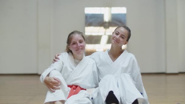 Προβολή ευτυχισμένων κοριτσιών με κιμονό να αγκαλιάζονται και να κάθονται στο γυμναστήριο — Αρχείο Βίντεο
