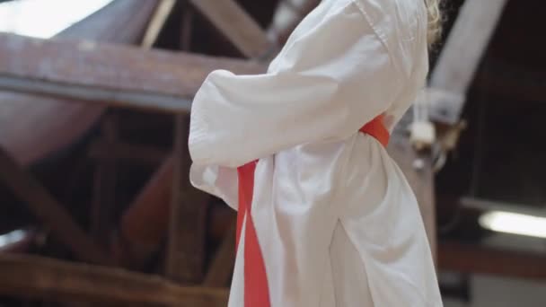 Девушка завязывая красный пояс на кимоно и складывая руки за спиной — стоковое видео