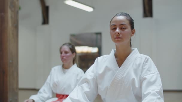 Vooraanzicht van schattige karateka zittend in lotuspositie op vloer — Stockvideo