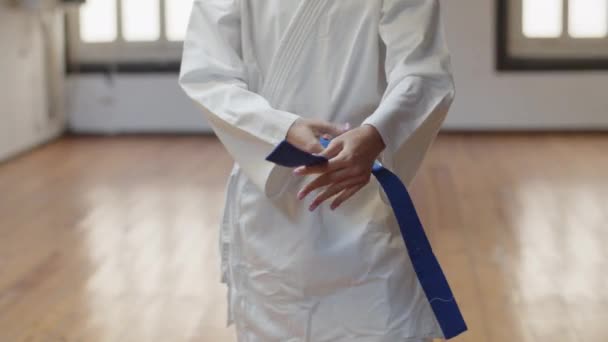 Vista frontal de chica irreconocible atando cinturón azul en kimono — Vídeos de Stock