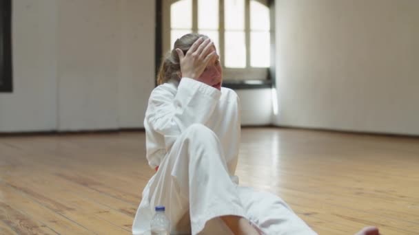Statický záběr unavené karateka pitné vody v tělocvičně — Stock video