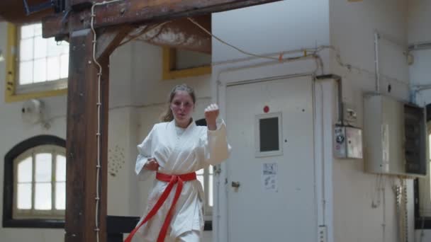 Framifrån av fokuserad flicka i kimono tränar karate i gym — Stockvideo