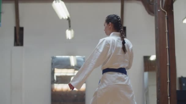 Tracking shot of karateka praciting kick jumps in gym — Stok Video