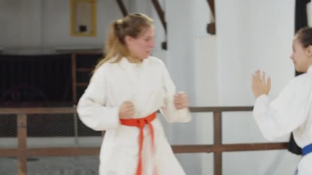 Toma de mano de chicas lindas en kimono practicando karate en el gimnasio — Vídeos de Stock