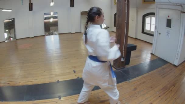 Tracking shot van gericht meisje oefenen karate bewegingen in de sportschool — Stockvideo