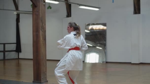 Spårning skott av fokuserad flicka i kimono öva karate i gym — Stockvideo