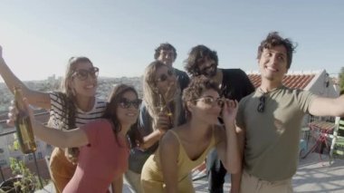 Mutlu erkekler ve kadınlar çatı katındaki partide ortak fotoğraf çekiyorlar.