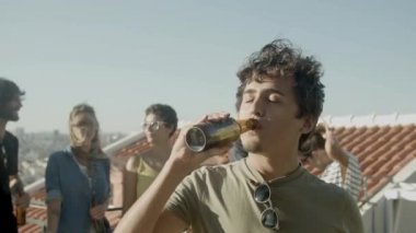 Kaygısız adam çatıdaki partide bira içip pizza yiyor.