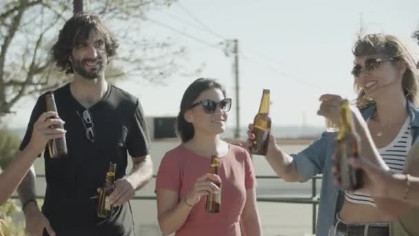 Ευτυχισμένοι φίλοι που στέκονται στην ταράτσα και χτυπάνε μπουκάλια μπύρας — Αρχείο Βίντεο