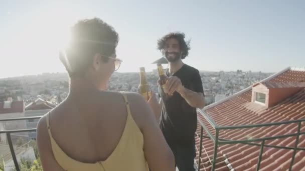 Щасливі коханці чіпляються за пляшки пива і танцюють на даху — стокове відео