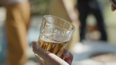 Elinde bardak tutan ve içine bira döken bir adam.