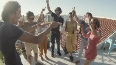 Çatıdaki partide arkadaşlarına pizza taşıyan mutlu bir adam.