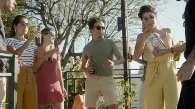 Mutlu arkadaşlar çatıdaki partide dans edip nacho yiyorlar.